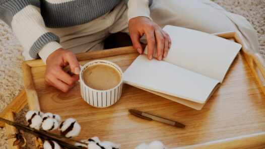 Woman with blank notebook and cup of coffee